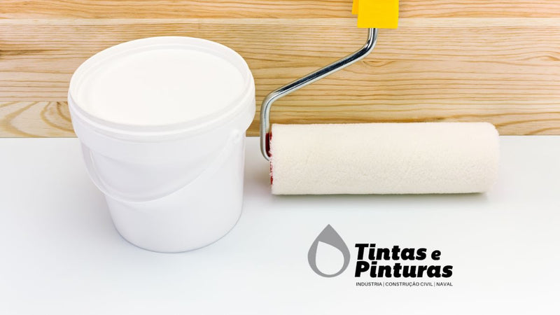 Recipiente de tinta plástica pousado sobre o chão. Ao lado encontra-se um rolo de pintura. Na imagem também é possível observar o logo da Tintas e Pinturas, uma empresa que comercializa tintas online, bem como na sua loja física, em Viana do Castelo.