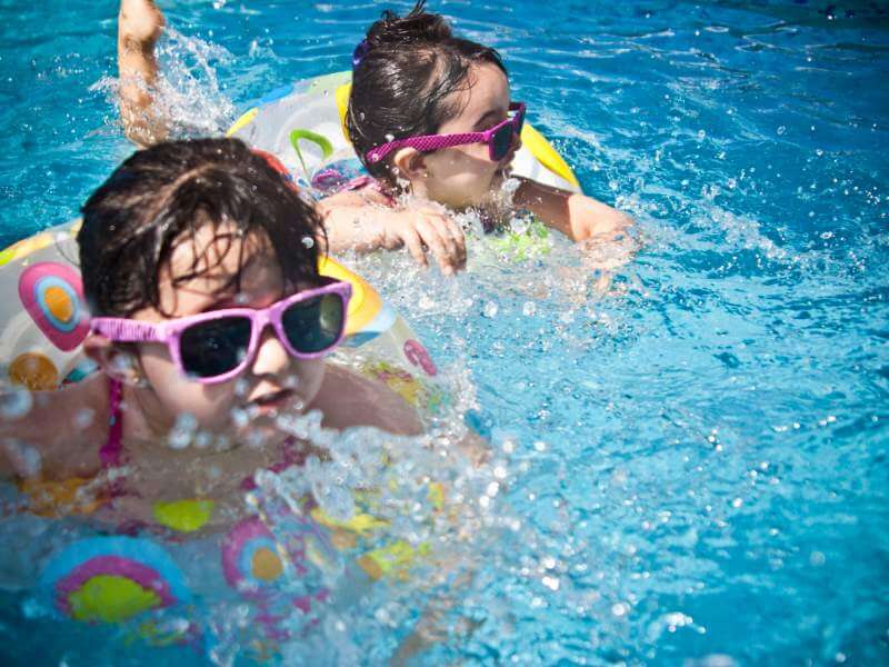 Duas crianças a divertirem-se numa piscina desinfetada pelas pastilhas de cloro para piscinas Clorgrou, da Grouht.