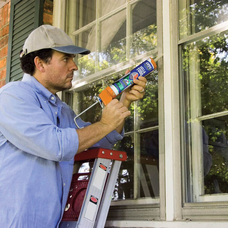 Aplicador de construção civil a utilizar o silicone neutro numa janela.