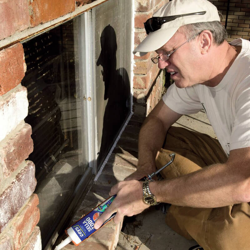 Aplicador a utilizar o silicone neutro veda tudo da ceys numa construção habitacional, neste caso numa janela envolta por tijolo.