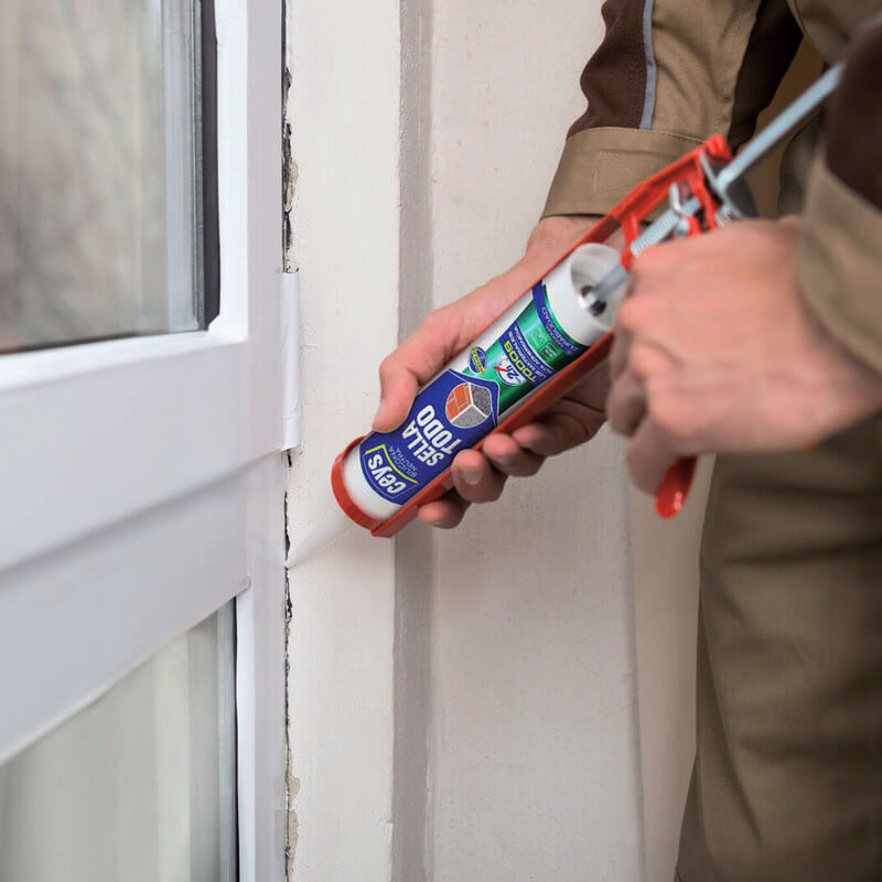 Utilizador a aplicar o silicone neutro veda tudo da ceys numa junta de uma porta habitacional.