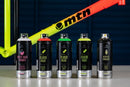 Latas de spray da Montana Colors posicionadas em frente a um quadro de bicicleta. As várias latas foram utilizadas na pintura do quadro: Spray White Base Primer, Spray Fluor Paint  Spray Acrylic Varnish.