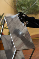 Pessoa a aplicar o Spray MTN PRO Stainless Steel Paint da Montana Colors numa prateleira de aço inoxidável. Esta tinta aerossol foi especialmente concebida para proteger superfícies de inox.