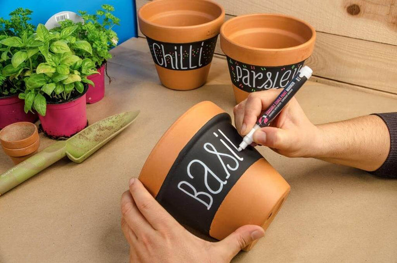 Vasos personalizados com o Spray MTN PRO Chalk Board Paint. Em cada um dos três vasos exibidos na imagem foi escrito com giz o nome da planta de sementes que neles será colocada.