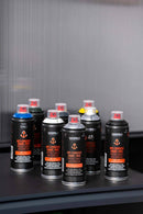 Latas de várias cores do spray tinta anticorrosiva da Montana Colors sobre uma mesa. 