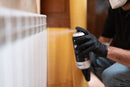 Pormenor de pintor a utilizar tinta spray para radiadores num radiador branco.